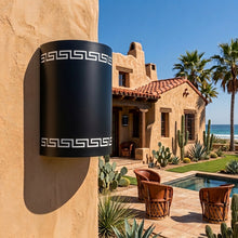 Load image into Gallery viewer, Greek key wall sconce in black, mounted on a stucco wall beside a tiled-roof courtyard