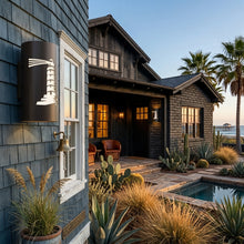 Load image into Gallery viewer, Lighthouse wall sconce in oil-rubbed bronze, mounted beside a window on a shingled beach house at dusk