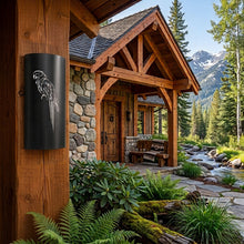 Load image into Gallery viewer, Macaw parrot wall sconce in black, mounted on a timber post at the entrance to a mountain lodge