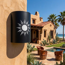 Load image into Gallery viewer, Southwest sun wall sconce in black, mounted on an adobe wall beside a tiled-roof courtyard